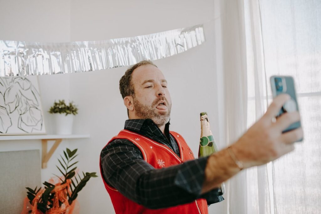 pexels-photo-6518750 A man in a holiday sweater takes a selfie while holding a beer, capturing a festive indoor scene.